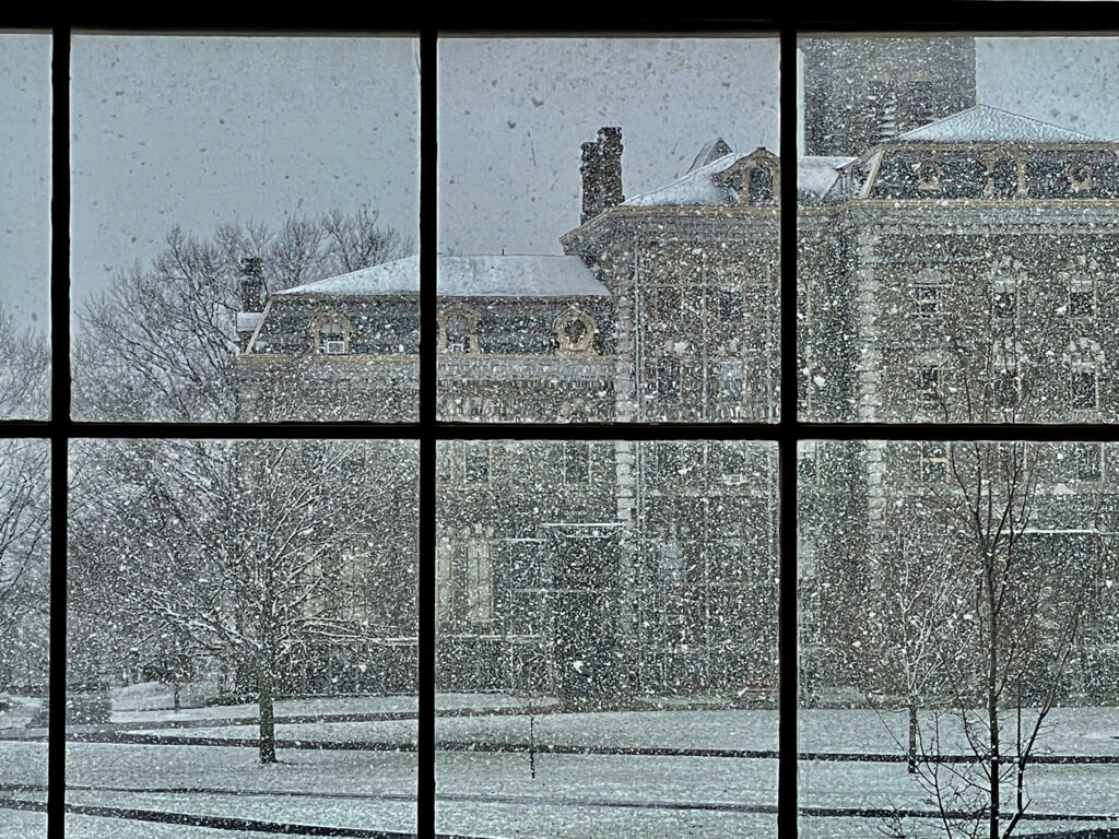 McGraw Hall and the Arts Quad during a heavy snow, viewed through a window pane