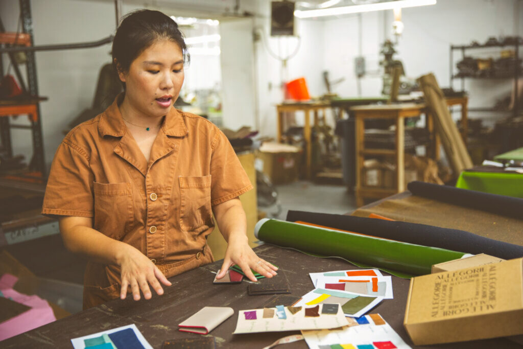 Heather Jiang looks at swatches of her colorful fruit leather on a table in front of her.