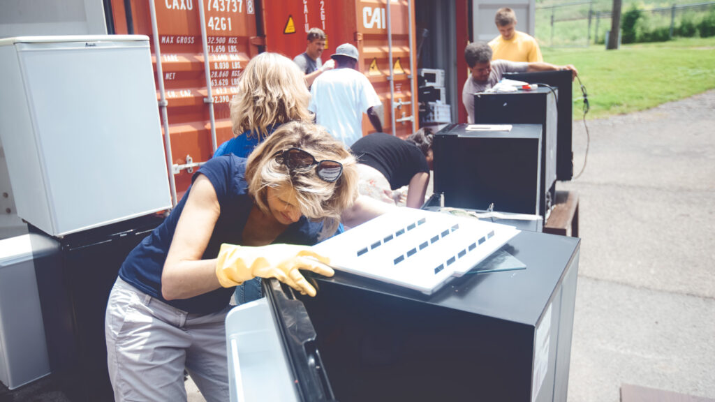 Volunteers for the dump and run sale carry mini fridges from storage containers.