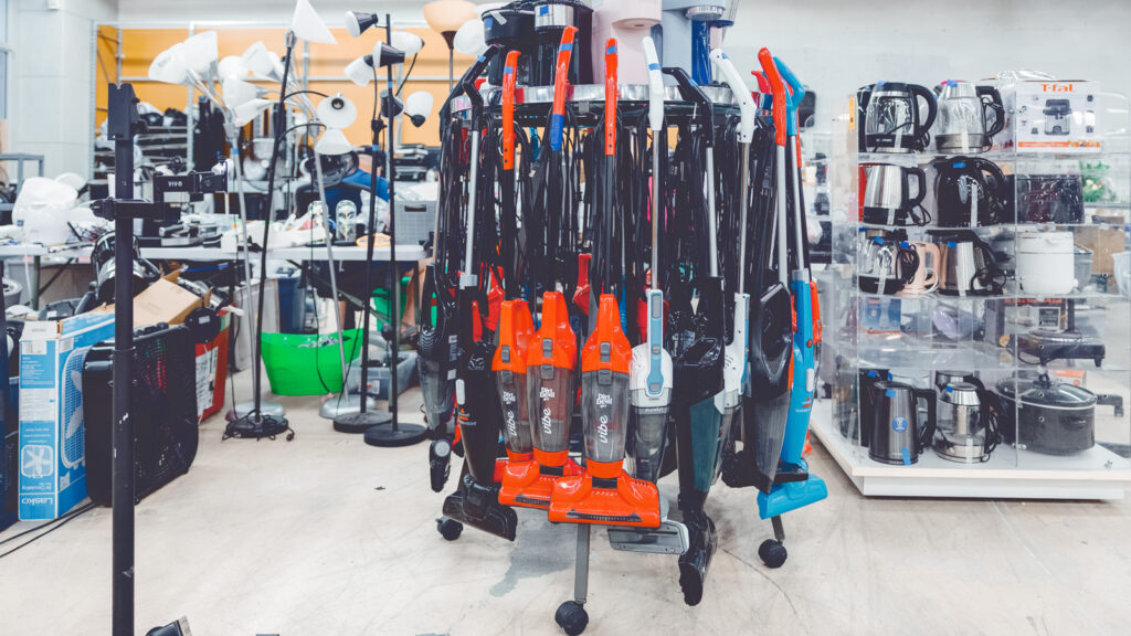 Vacuums hang on a circular rack, teapots, filtered water pitchers, and crockpots fill shelves, and standing lamps are clustered together at the site of where the Dump and Run sale will be in the Ithaca Mall.
