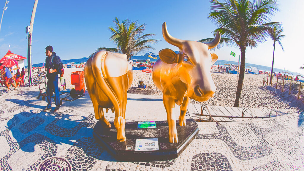 A gold fiberglass cow cut in half on a beach