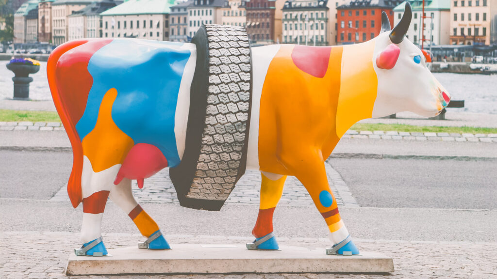 A fiberglass cow wearing a tire around its waist