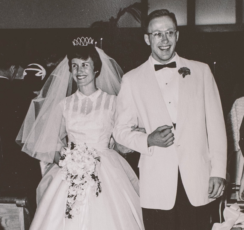 Peggy Flynn Dunlop walks arm-in-arm down the aisle in her wedding dress and veil with husband David Dunlop.
