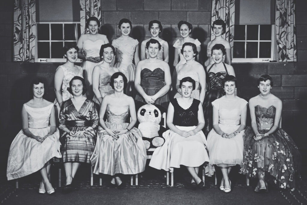 Peggy Dunlop and 15 other woman wearing dresses smile for a photo before heading to formal.