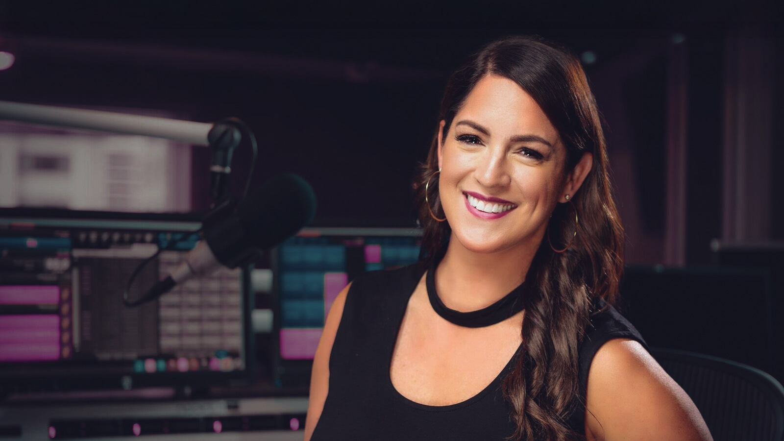 Sarah Spain smiles in a studio with a microphone to the side of her face.