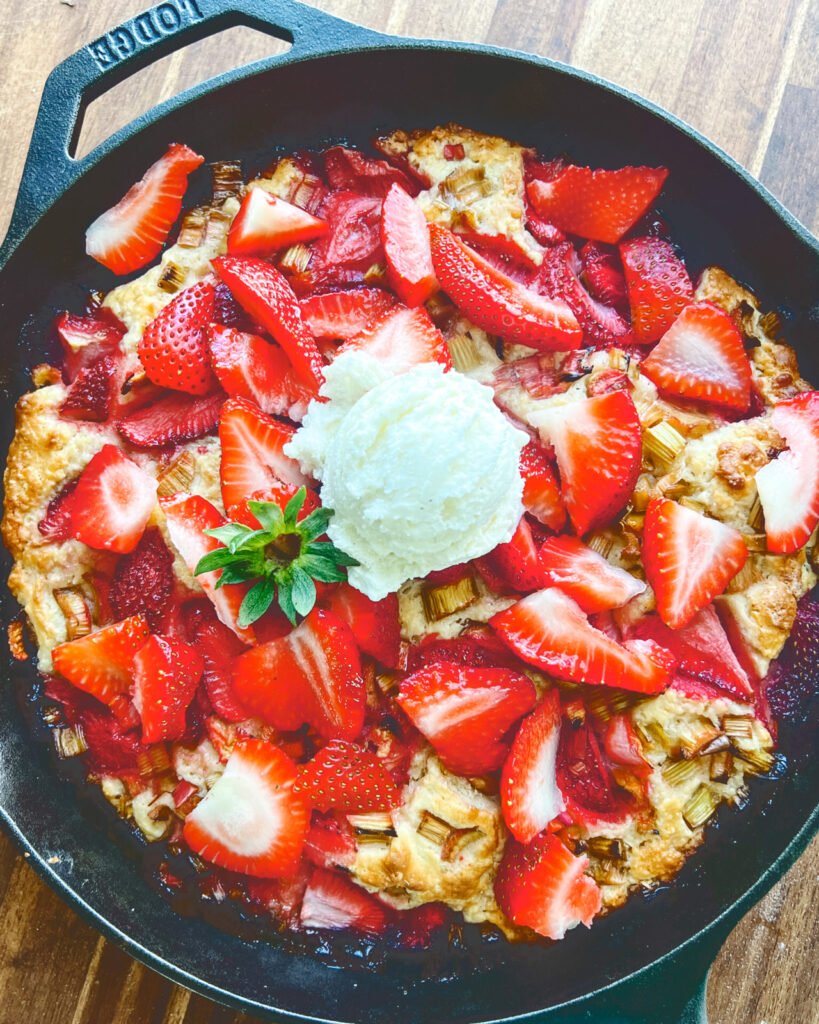 Skillet Strawberry Rhubarb Shortcake with chopped strawberries and a scoop of vanilla ice cream on top.
