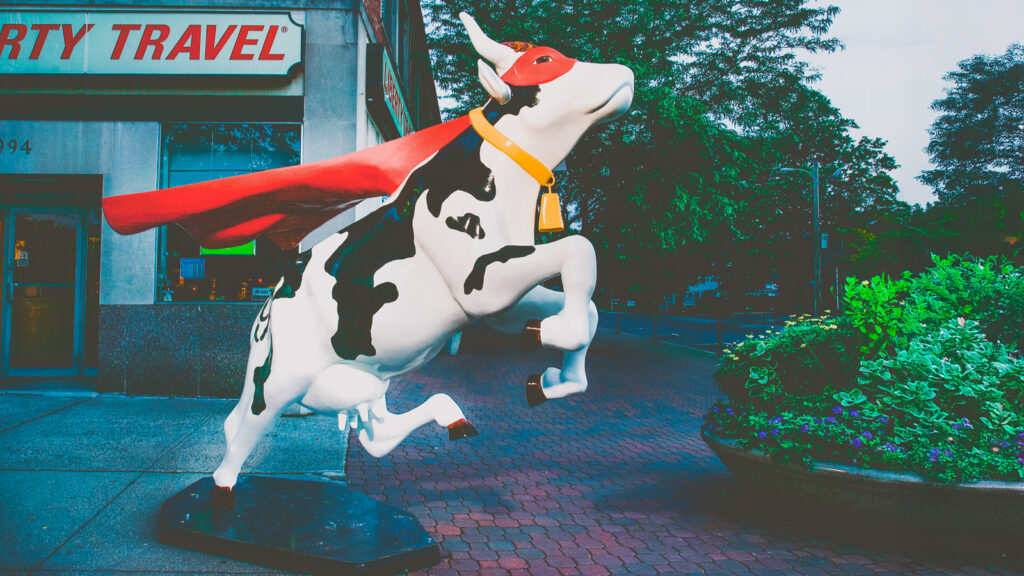 A fiberglass cow wearing a cape and mask