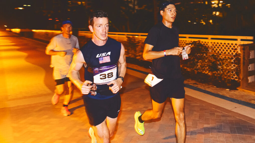 Alan Nawoj and two other runners run at night down a sidewalk in Miami during the last race.