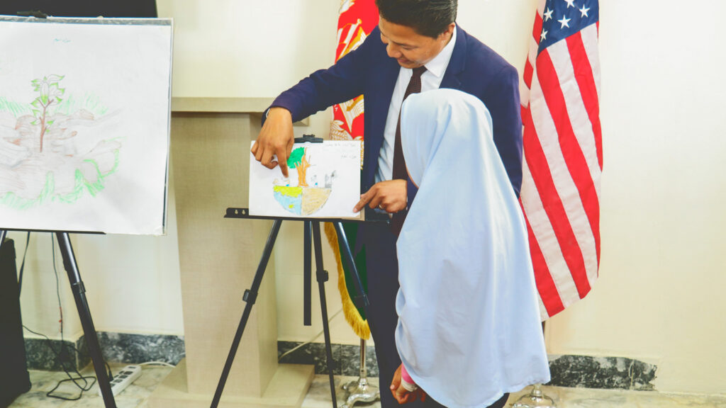 Hamidullah Nikzad with a female student looking at an easel with a drawing of a tree on it