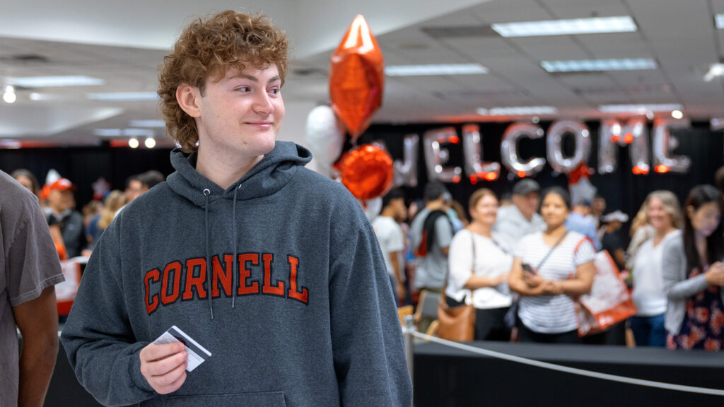 A student holds his issued ID card at the welcome center at the Ithaca mall during Move-In Weekend, 2025