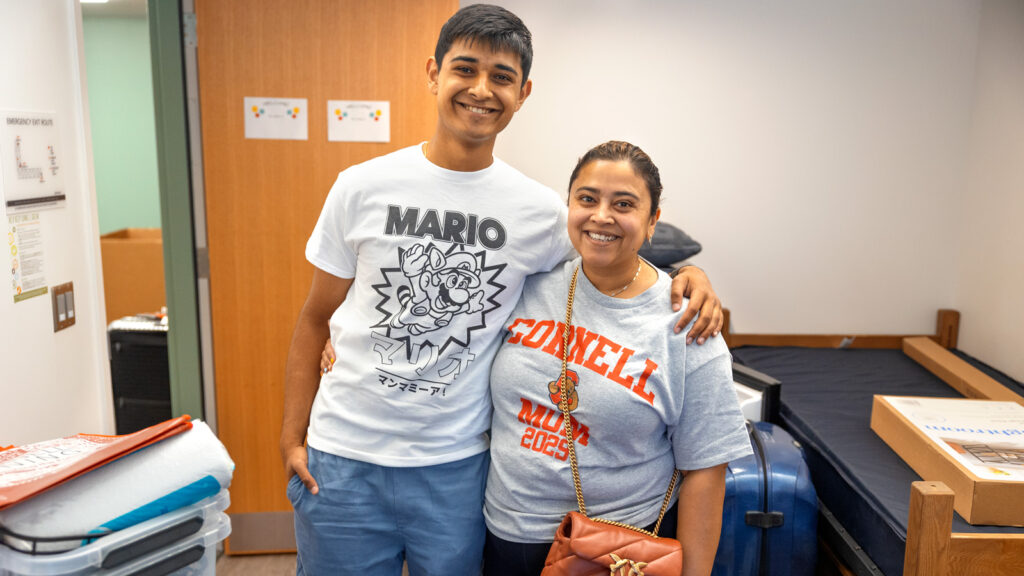 a student and parent pose for a photo in a residence hall room during Move-In Weekend, 2025