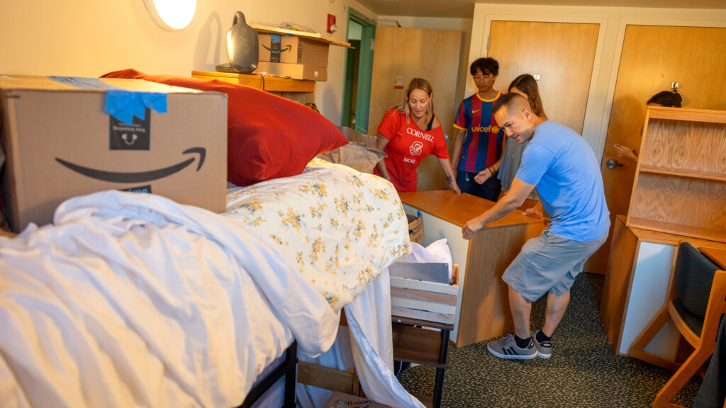 a student and family members move furniture into a residence hall room during Move-In Weekend, 2025