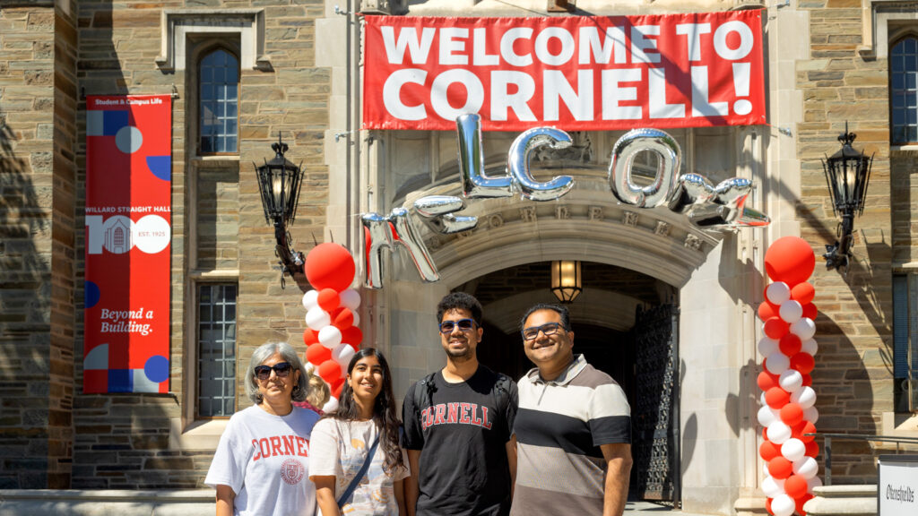 a student and family members pose in front of Willard Straight Hall during Move-In Weekend, 2025