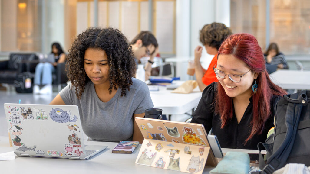 Two students look at laptop and tablet screens in a classroom on the first day of classes, fall 2025