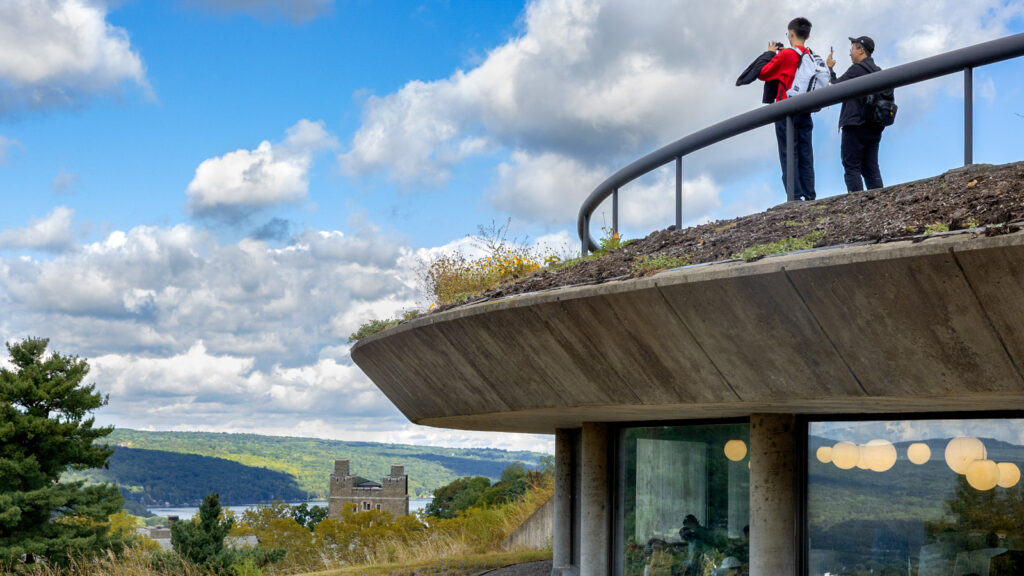 Students wearing backpacks take photos of the view of the lake from the viewing area atop the Slope