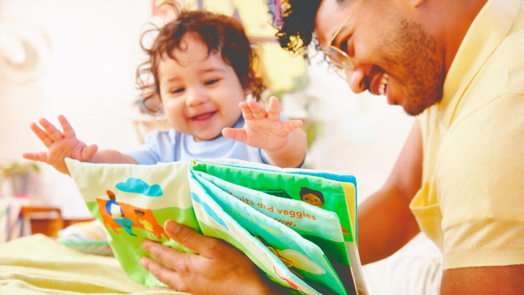 a father reads a soft Lovevery early reader book to a toddler