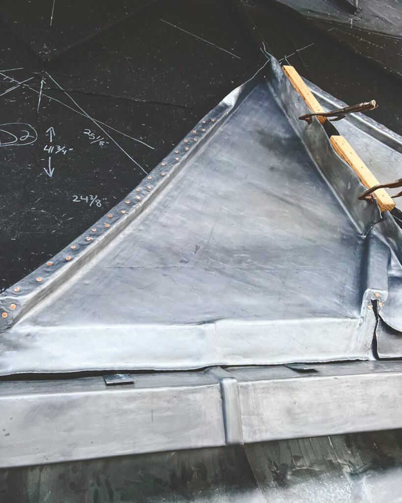the sheet lead being formed over wood battens to create the chevron pattern