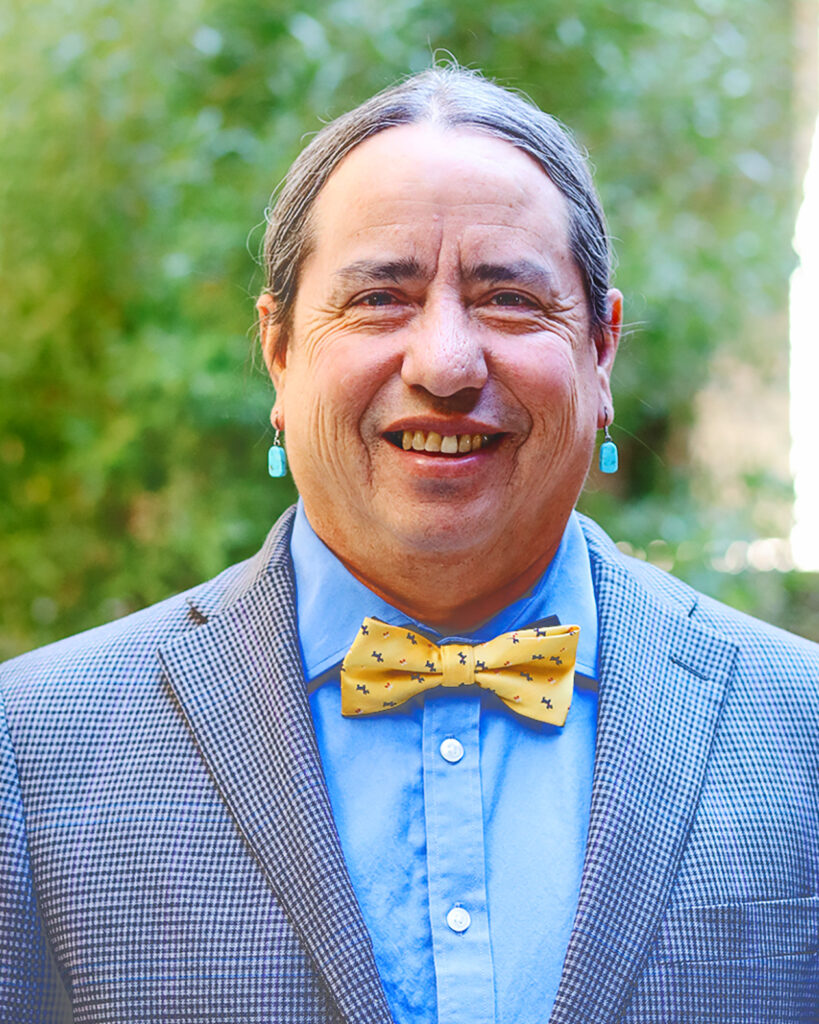 Michael Kotutwa Johnson wears a bowtie and suit and smiles.