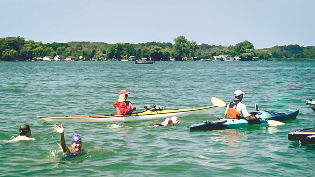 Claire De Boer waves while in the water near several kayakers