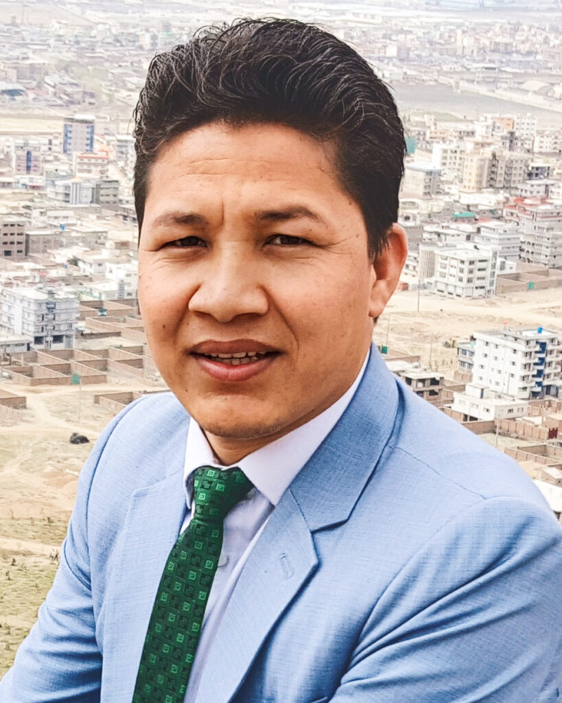 Hamidullah Nikzad wearing a suit with a city in Afghanistan in the background