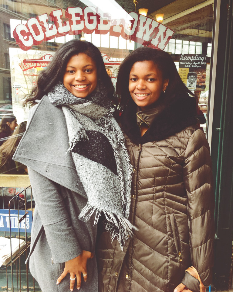 Shelby and Lauren Holland stand in front of the window wearing winter jackets at Collegetown Bagels.