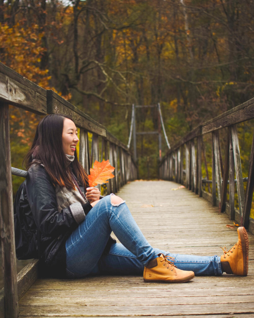 Michelle Shin sitting on a bridge holding a leaf
