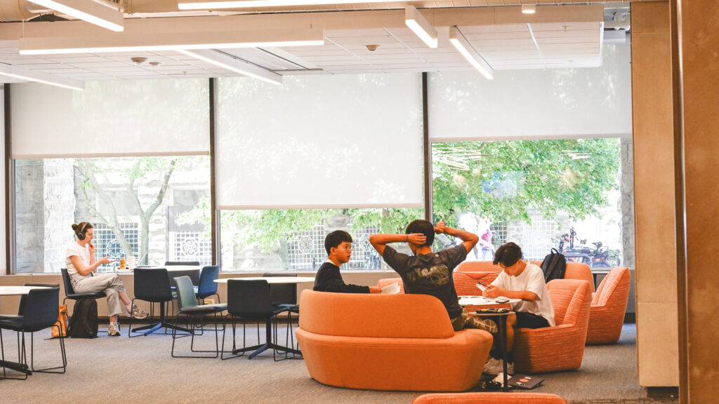 patrons sit near the windows on the Arts Quad side of the renovated main floor of Olin Library
