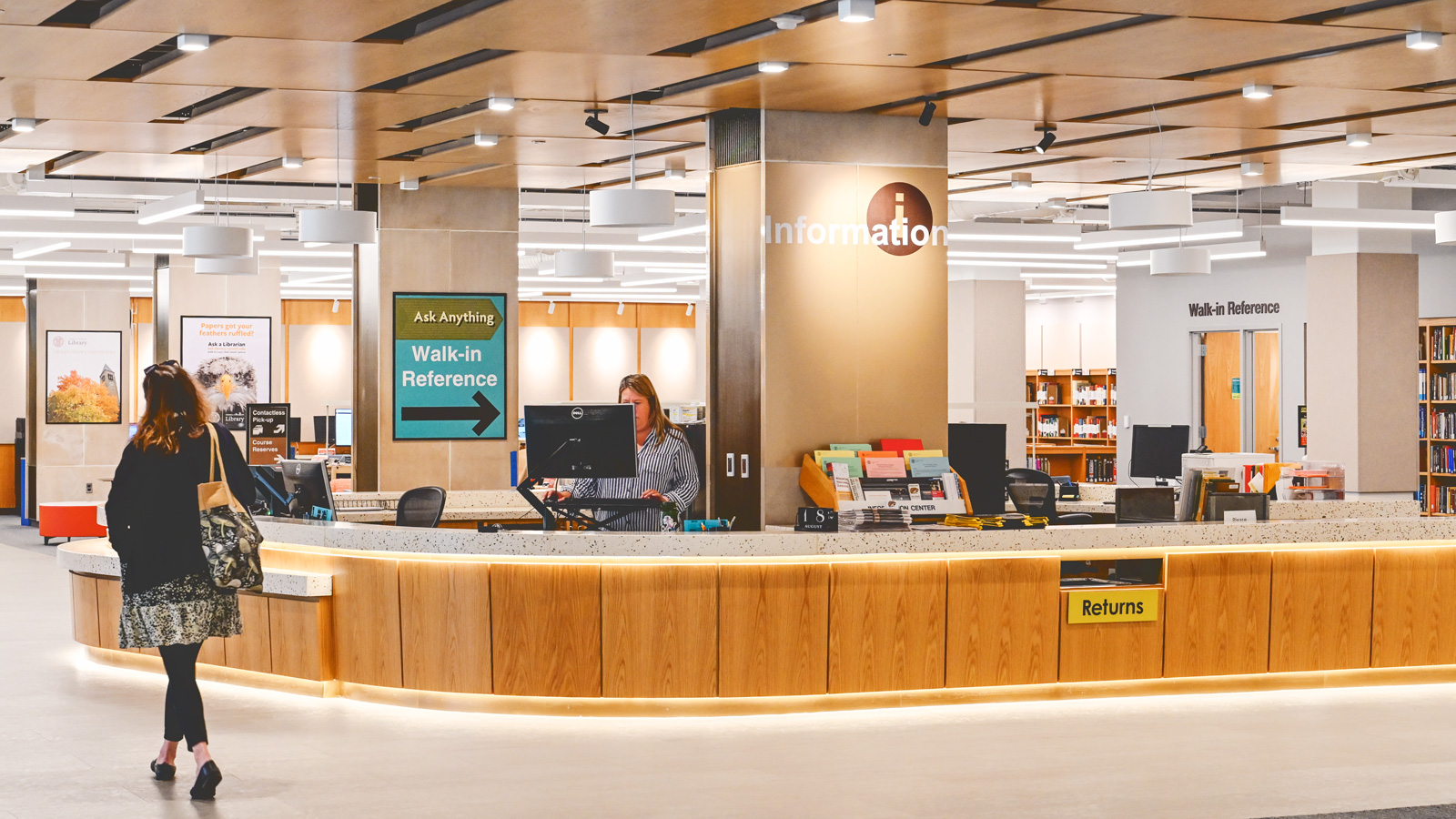 a patron passes the new, combined circulation and help desk in the renovated main floor of Olin Library