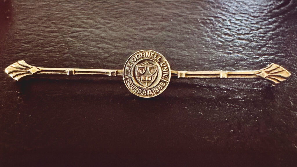 a delicate brooch with a tiny University insignia at its center