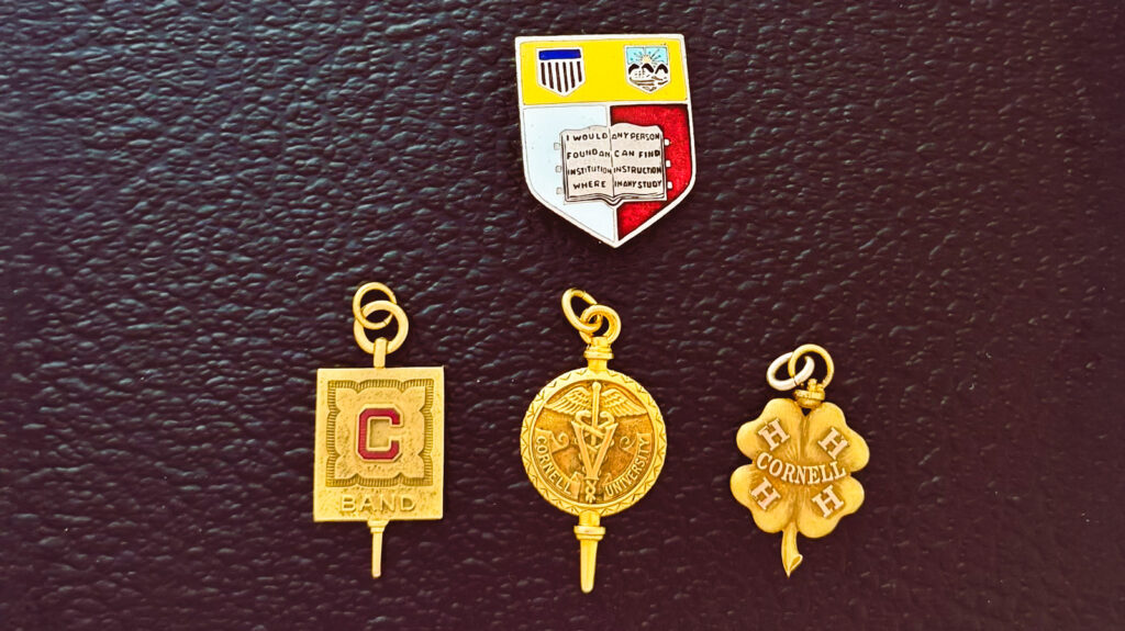 Pins displaying the Cornell insignia and seals for the band, veterinary college, and 4-H club