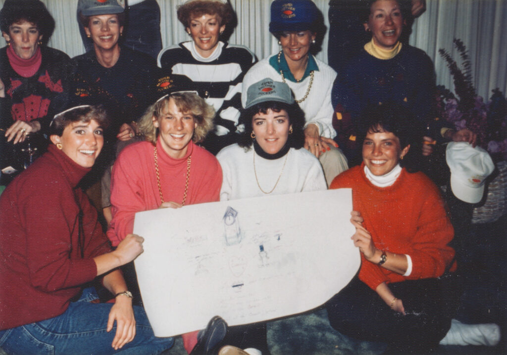 Anne Meinig ’87, bottom right, pictured with members of the Cornell women's tennis team and several parents during a trip to Japan, holding a large drawing used to remember the lyrics to the Cornell "Alma Mater"