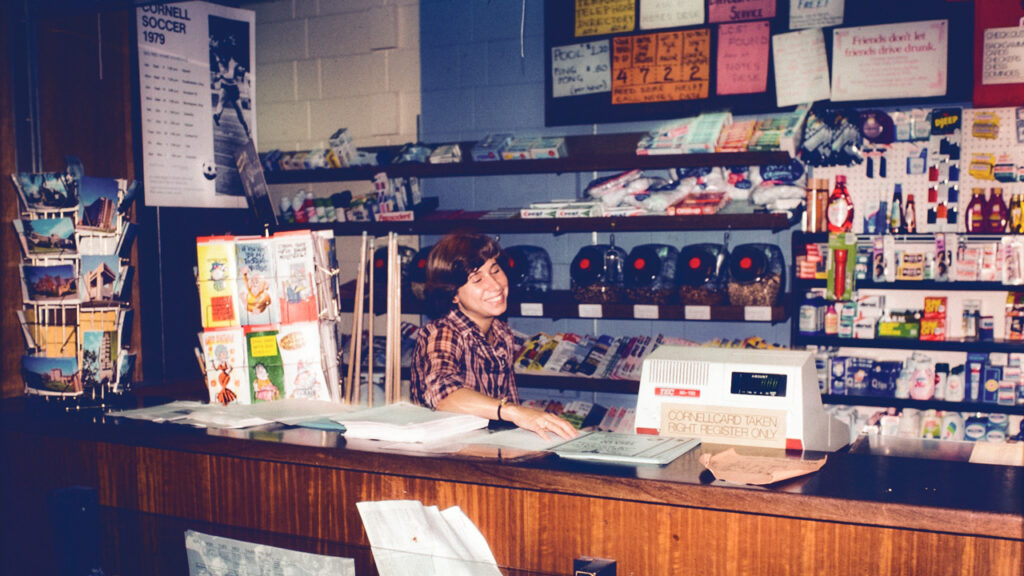 A view of the welcome desk at Willard Straight Hall and a student worker behind the counter, 1979