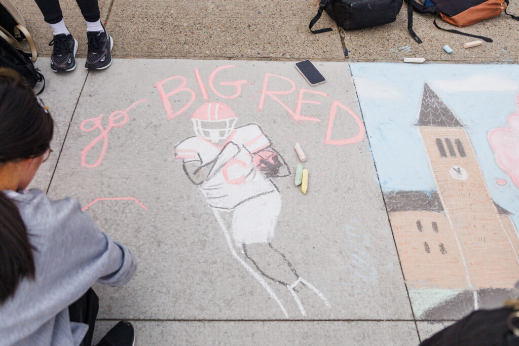 A chalk drawing of a Big Red football player running with the football with writing that says "Go Big Red" for the Chalk Challenge event during spirit week.