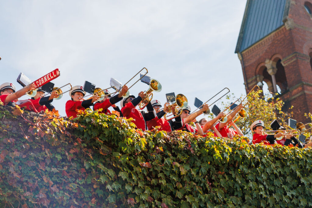 The Big Red band plays from the top of a greenery-covered wall.