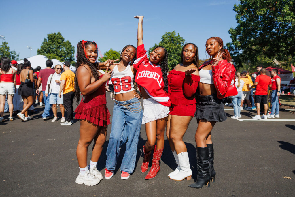 Five girls pose in their red and white Cornell spirit wear during homecoming.