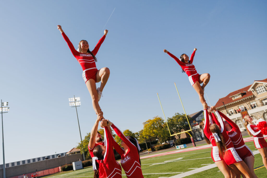 Cheerleaders perform a routine with two flyers in the air during the homecoming football game.