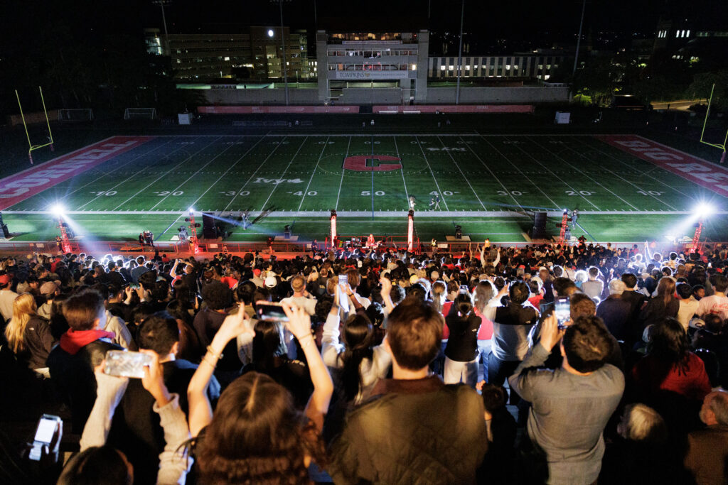 Spectators watch the drone and laser show from the bleachers in Schoelkopf Field.