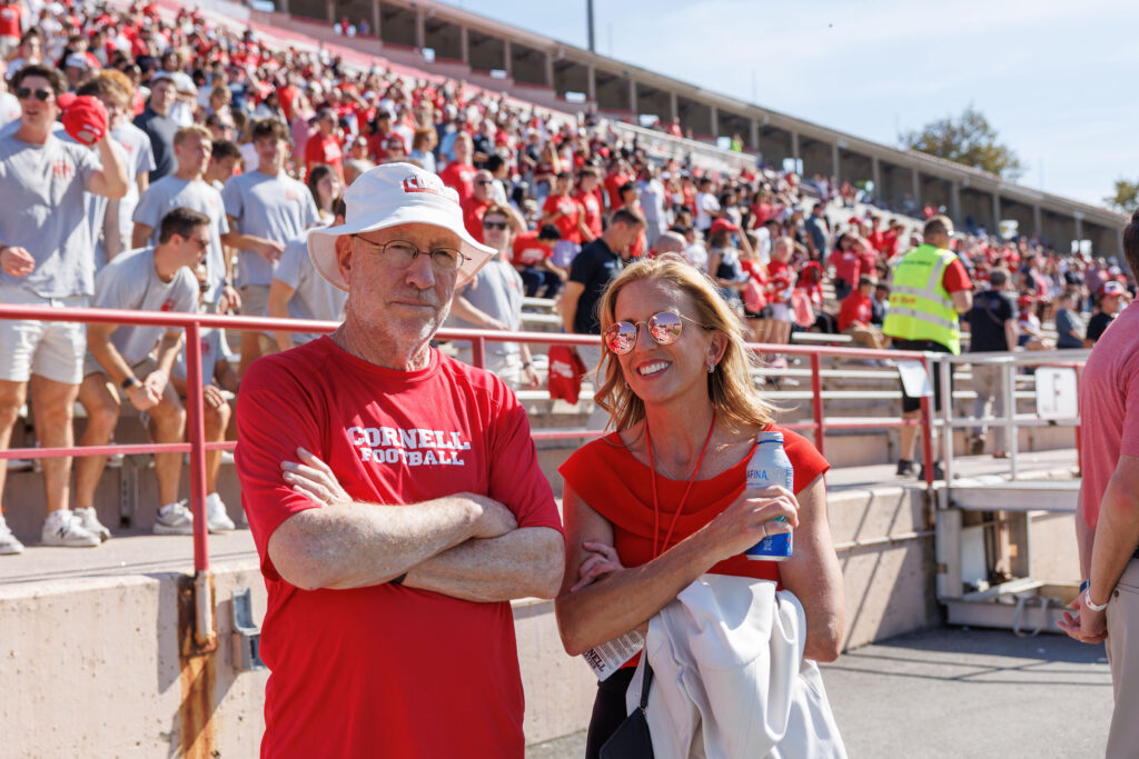 President Michael I. Kotlikoff and XXX stand and watches the game at Schoellkopf Field in front of a sea of fans behind him in the bleachers during the homecoming football game against Colgate.