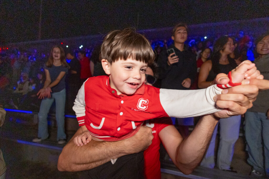 A little boy cheers in his Cornell jacket during the drone and laser show.
