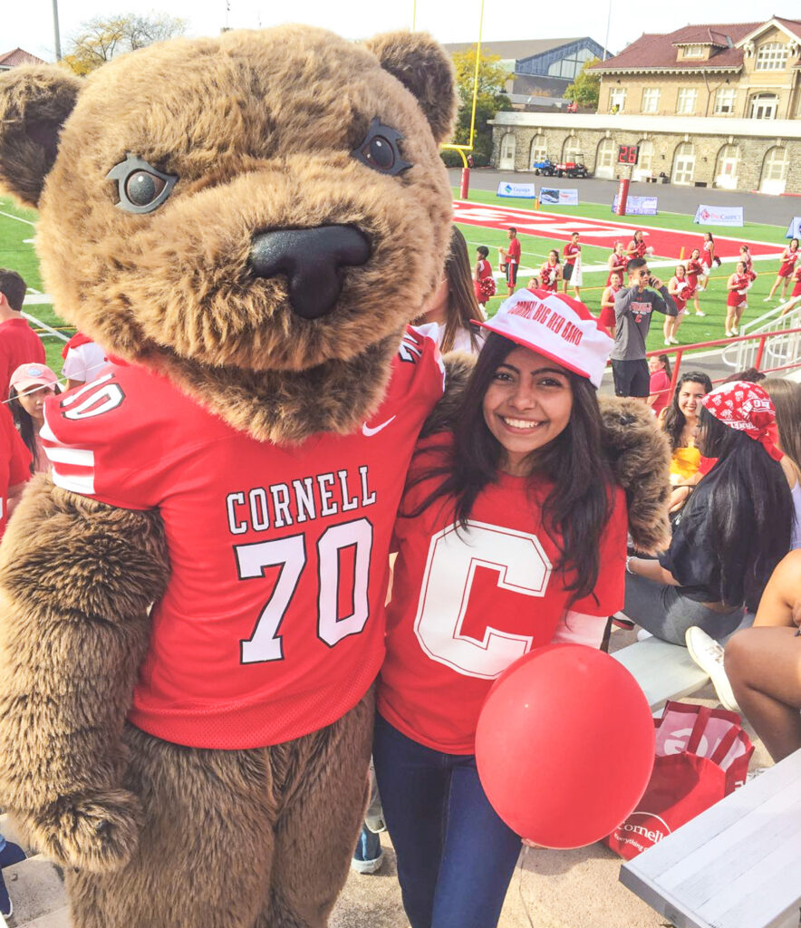 Aishwarya Lahariya wearing a Cornell shirt and hat at a football game with touchdown.