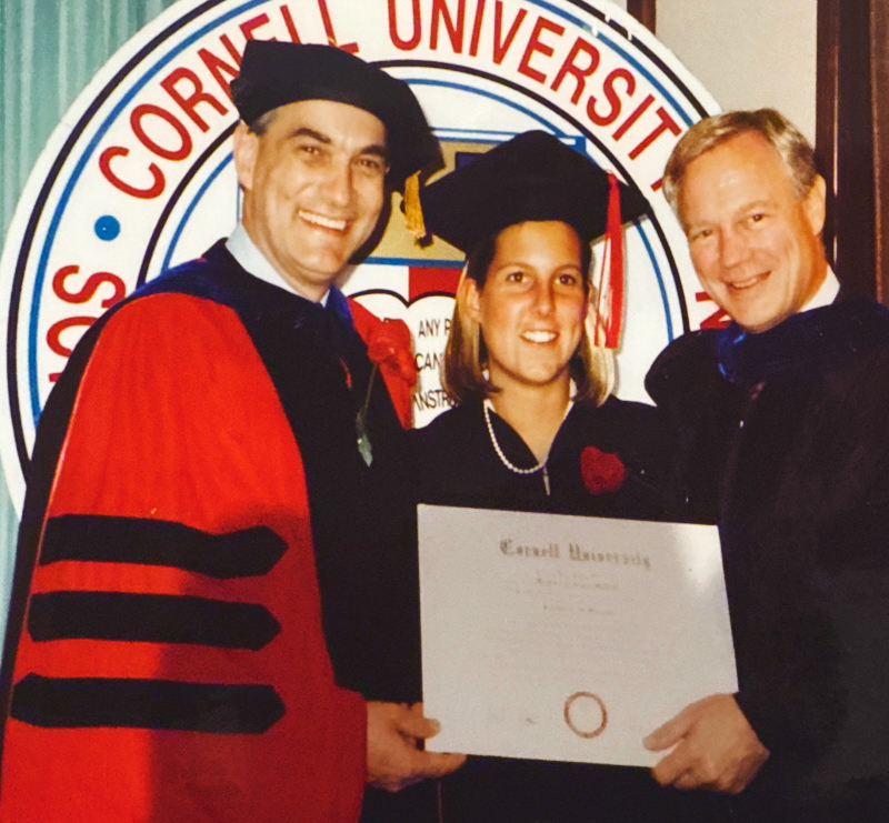 Kim Hehir holding her diploma at commencement in her academic regalia.