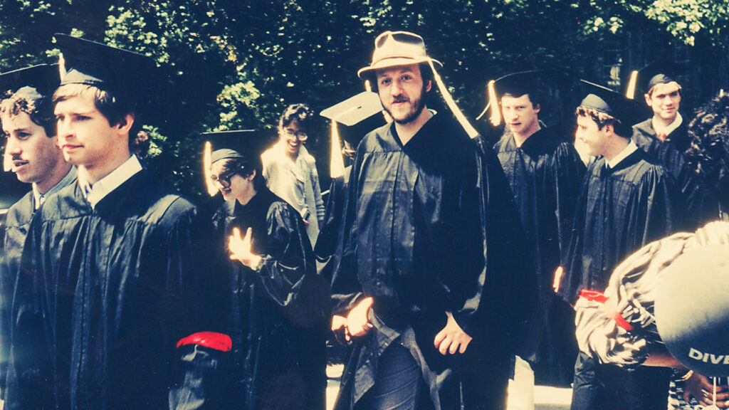 Jim Perkins walks with other graduates in his gown during commencement.