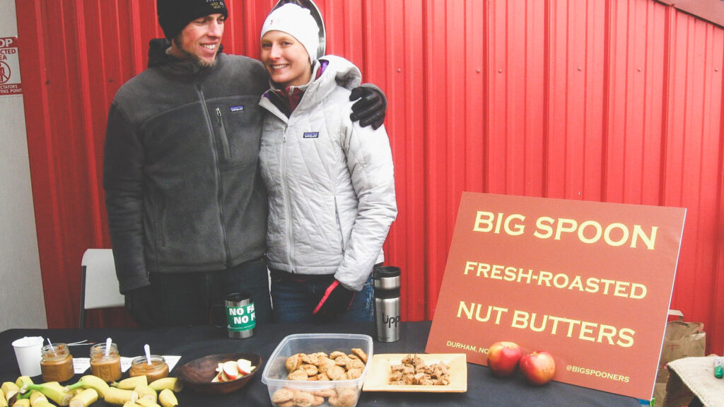 Megan Overbay and her husband with samples of nut butter and banana on display at a bike race.