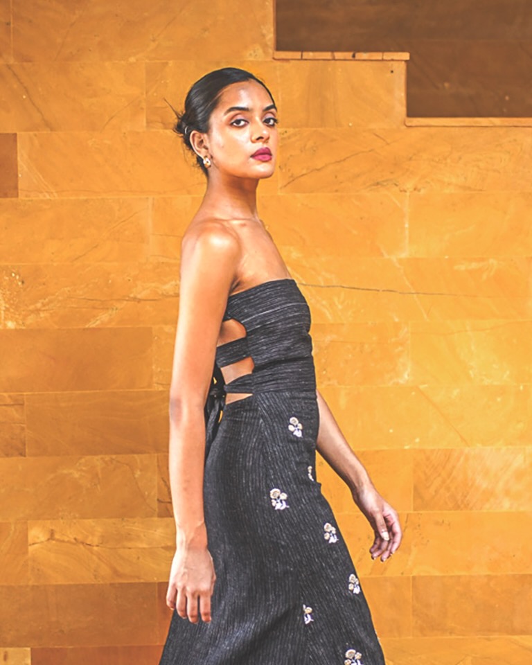 A model for Jiwya walks to the side wearing a black dress with flowers on it.