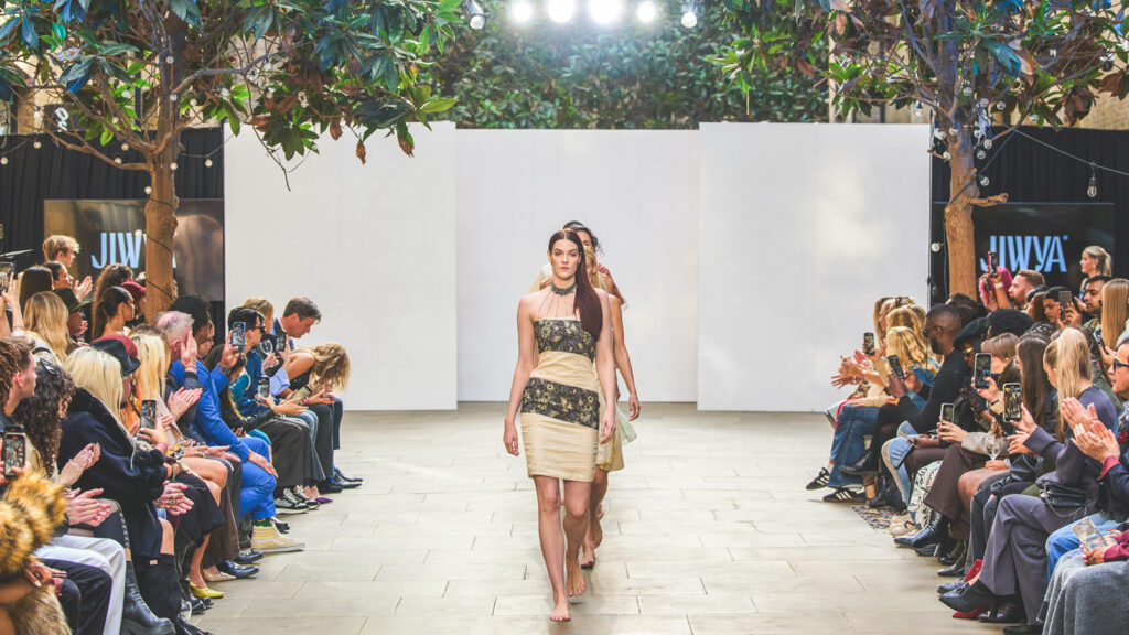 Models walk down the runway during London Fashion Week wearing Jiwya's new collection, which includes a tan and black patterned dress.