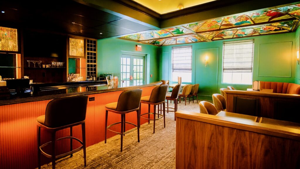 a hotel bar with green walls and a colorful glass ceiling
