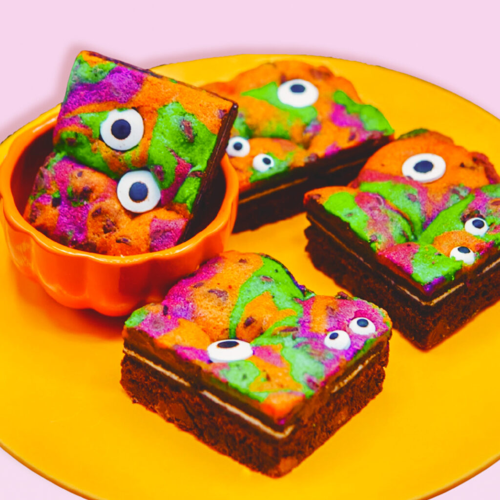 Halloween-themed brookies in green, purple, and orange with edible google-eyes on a plate.