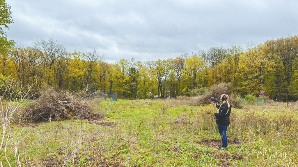 Karianne Kapfer holding a microphone in a wooded clearing