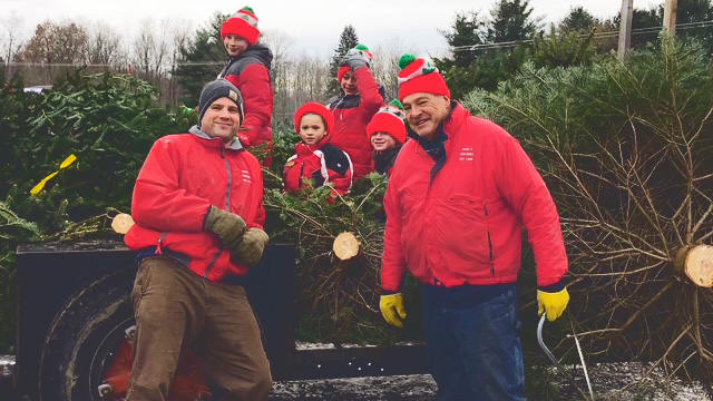 Jason Moore smiles in front of a truck fulled with Christmas trees with his father, Richard, and his kids.