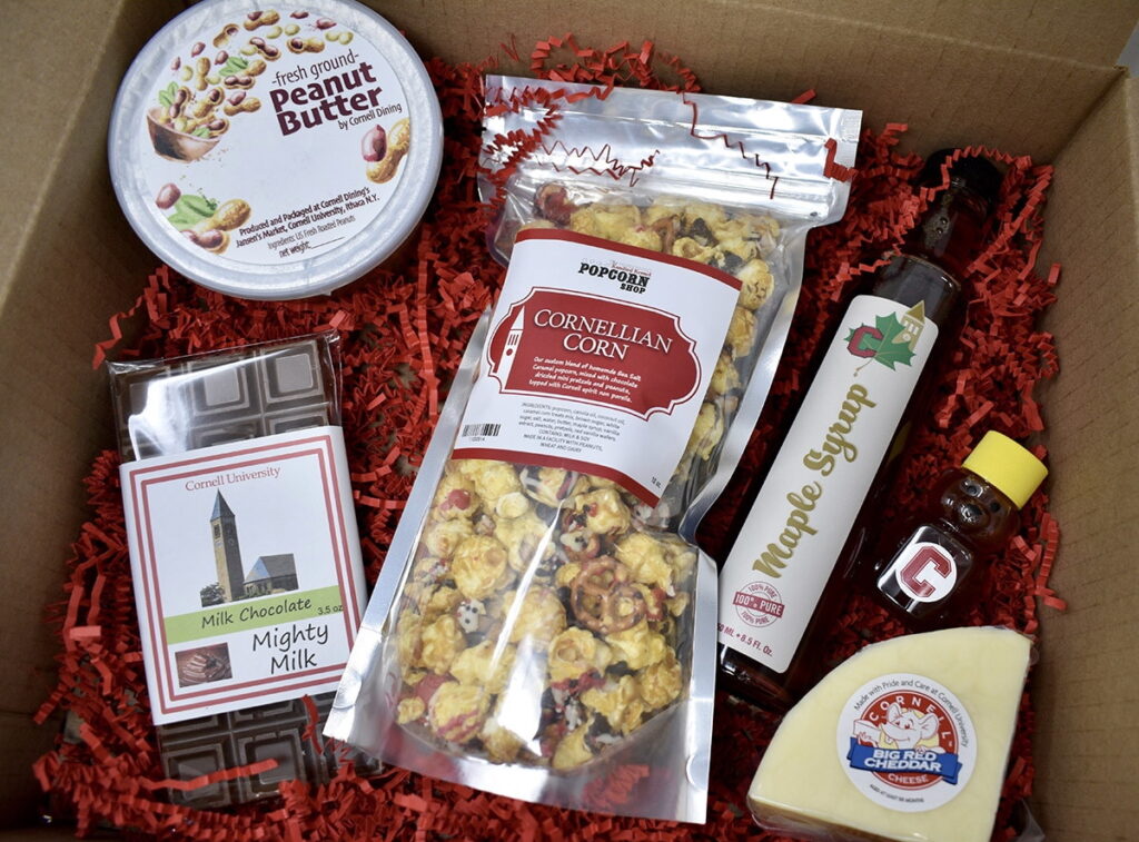 A box with Cornell-branded items including fresh ground peanut butter, caramel popcorn, milk chocolate, maple syrup, honey, and cheese in it.